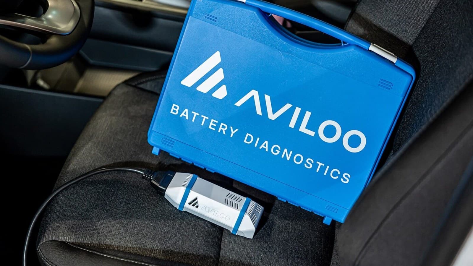 AVILOO akkumulátor-diagnosztikai eszköz elektromos autóhoz csatlakoztatva, az ingyenes akkumulátor-garancia illusztrációja.