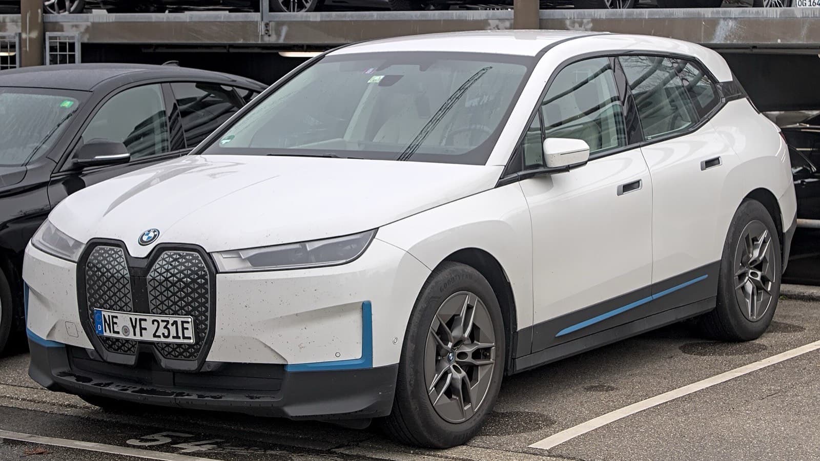 BMW iX vizsgálati hibák: fehér BMW iX elektromos szabadidő-autó háromnegyedes elölnézetben, a visszahívások illusztrációja.