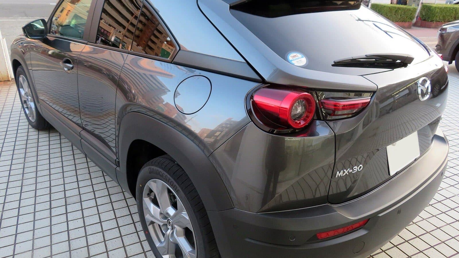 Mazda MX-30 vizsgálati hibák: sötétszürke Mazda MX-30 elektromos autó hátsó nézetben, MX-30 típusjelöléssel.