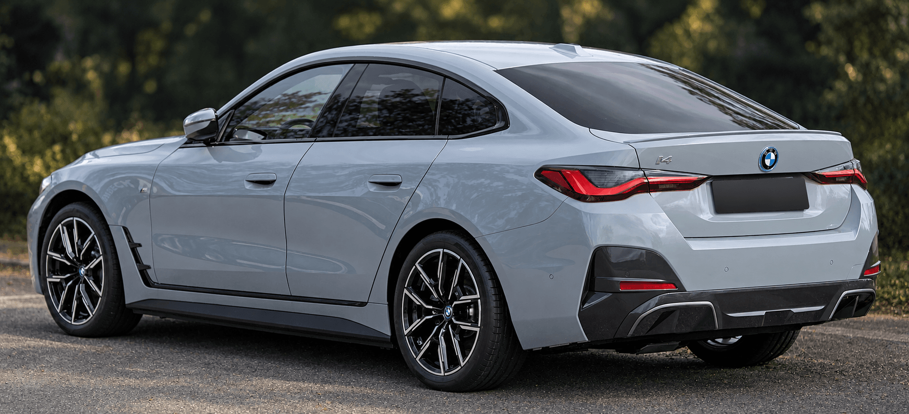 BMW i4 elektromos autó hátsó háromnegyedes nézetben, anonimizált rendszámmal.