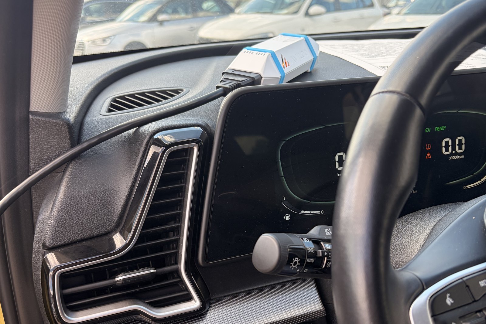 AVILOO Box a Kia Sportage PHEV műszerfalán, a helyszíni független akkumulátorteszt előkészítve, a diagnosztikai csatlakozóra kötve. — EVX elektromos autó átvizsgálás és állapotfelmérés.